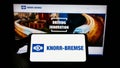 Person holding smartphone with logo of German manufacturing company Knorr-Bremse AG on screen in front of website. Royalty Free Stock Photo