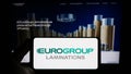 Person holding smartphone with logo of Italian company EuroGroup Laminations S.p.A. on screen in front of website.