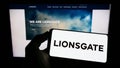 Person holding smartphone with logo of Lions Gate Entertainment Corporation (Lionsgate) on screen in front of website.