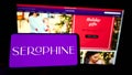 Person holding smartphone with logo of maternity fashion company Seraphine Group plc on screen in front of website.