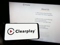 Person holding smartphone with logo of parental control company Clearplay Inc. on screen in front of website.