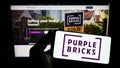 Person holding smartphone with logo of real estate company Purplebricks Group plc on screen in front of website. Royalty Free Stock Photo