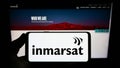 Person holding smartphone with logo of satellite company Inmarsat Global Limited on screen in front of website. Royalty Free Stock Photo