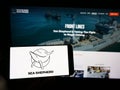 Person holding smartphone with logo of Sea Shepherd Conservation Society (SSCS) on screen in front of website.