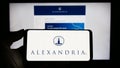 Person holding smartphone with logo of US company Alexandria Real Estate Equities Inc. on screen in front of website.