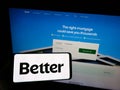 Person holding smartphone with logo of US financial company Better Mortgage (Better.com) on screen in front of website.