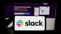 Person holding smartphone with logo of US software company Slack Technologies LLC on screen in front of website. Royalty Free Stock Photo