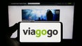 Person holding smartphone with logo of US ticket exchange platform company Viagogo on screen in front of website.