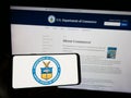 Person holding smartphone with seal of the United States Department of Commerce (DOC) on screen in front of website. Royalty Free Stock Photo