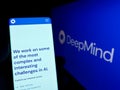 Person holding smartphone with webpage of AI company DeepMind Technologies Limited on screen in front of logo.