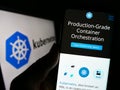 Person holding smartphone with website of container orchestration system Kubernetes on screen in front of logo.