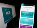 Person holding smartphone with website of French hydrogen company HDF Energy on screen in front of logo.