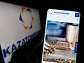 Person holding smartphone with website of Kazakh uranium mining company Kazatomprom on screen in front of logo. Royalty Free Stock Photo