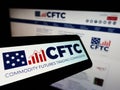 Smartphone with logo of American Commodity Futures Trading Commission (CFTC) on screen in front of website.