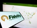 Smartphone with logo of American company Fidelity Investments (FMR LLC) on screen in front of website.