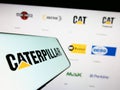 Smartphone with logo of American heavy equipment company Caterpillar Inc. on screen in front of website.