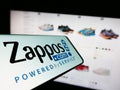 Smartphone with logo of American online shop company Zappos.com LLC on screen in front of business website.