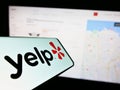 Smartphone with logo of American review platform company Yelp Inc. on screen in front of business website.