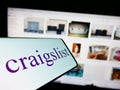 Smartphone with logo of classified advertisements company Craigslist Inc. on screen in front of website. Royalty Free Stock Photo