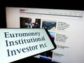 Smartphone with logo of company Euromoney Institutional Investor plc on screen in front of website.