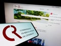 Smartphone with logo of French Commission de Regulation de l\'Energie (CRE) on screen in front of website.