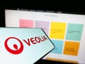 Smartphone with logo of French company Veolia Environnement SA on screen in front of business website.