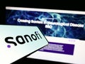 Smartphone with logo of French pharmaceutical company Sanofi S.A. on screen in front of business website.