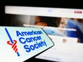 Smartphone with logo of organization American Cancer Society (ACS) on screen in front of website.