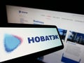 Smartphone with logo of Russian natural gas company Novatek on screen in front of business website.