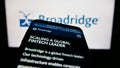 Smartphone with website of US company Broadridge Financial Solutions Inc. on screen in front of logo.