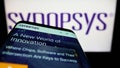 Smartphone with website of US technology company Synopsys Inc. on screen in front of business logo.