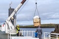 Employee loads cargo onto the Ferry Baldur in Iceland, as a father and son passengers watch