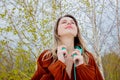 Style adult woman with headphones and burgundy color blouse on birch trees background Royalty Free Stock Photo