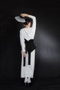 Beautiful young woman in a white Asian suit on a black background. The style of a modern geisha in the studio.