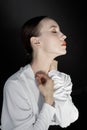 Beautiful young woman in a white Asian suit on a black background. The style of a modern geisha in the studio.