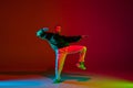 Stylish sportive boy dancing hip-hop in stylish clothes on colorful background at dance hall in neon light. Youth Royalty Free Stock Photo