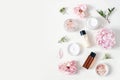 Styled beauty composition. Skin cream jar, tonicum bottle, roses, peony flower and Himalayan salt on white table