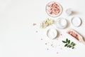 Styled beauty composition. Skin cream, tonicum bottle, dry flowers, rose and Himalayan salt on white table background