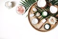 Styled beauty composition. Skin creams, makeup bottle, rose and pebble stones on wooden tray. Coconuts, tropical palm