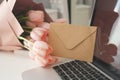 Styled feminine desk workspace with pink tulips, laptop computer and envelope Royalty Free Stock Photo