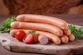 Styled Frankfurter sausages on wooden board with tomatoes and green herbs