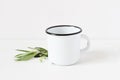 Styled stock photo. Feminine still life composition with blank white metal coffee enamel mug and green olive branch on