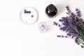 Styled summer beauty composition. Essential, massage oil, lavender flowers bouquet, bath salt on white wooden table Royalty Free Stock Photo