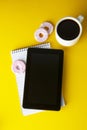 Styled yellow, food backdrop. Unhealthy lunch, snack with coffee, cookies, digital tablet. work space, lunch at work table. Top