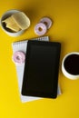 Styled yellow, food backdrop. Unhealthy lunch, snack with coffee, cookies, digital tablet. work space, lunch at work table. Top