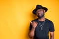 Stylish african american man in a hat and glasses points his finger to the side with interest Royalty Free Stock Photo