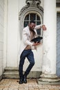 Stylish african american man wear beige jacket and  black hat with sunglasses pose against vintage window Royalty Free Stock Photo