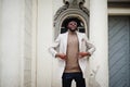 Stylish african american man wear beige jacket and  black hat with sunglasses pose against vintage window Royalty Free Stock Photo