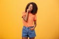 Stylish African American slim woman with curly medium hair holding hand in denim shorts tilting head, rubbing neck while Royalty Free Stock Photo