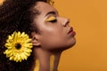 Stylish african american woman with artistic make-up and gerbera in hair dreaming